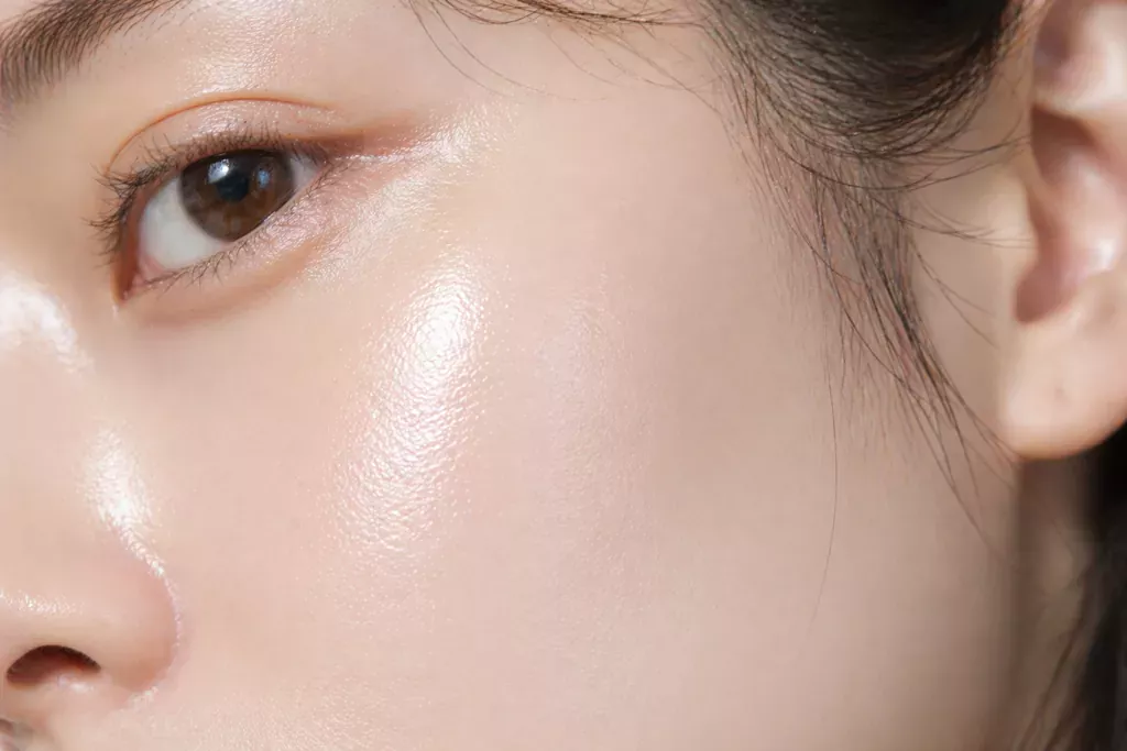 K-Beauty Niacinamide Guide: Mastering Niacinamide Benefits for Glass Skin 2 Macro close-up of a person's smooth and luminous cheek, perfectly illustrating the Niacinamide Benefits for Glass Skin and its pore-blurring efficacy.