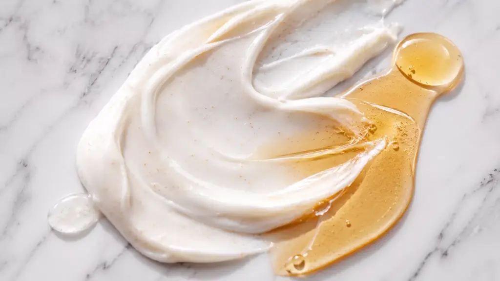 K-Beauty Glow Secret: Unlocking Propolis Extract Benefits for Skin 3 A smooth texture smear mixing a white ceramide barrier cream and golden serum to maximize Propolis Extract Benefits for Skin.