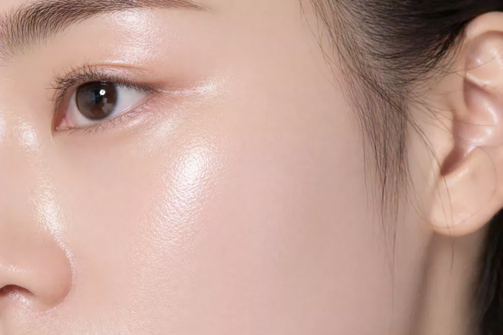 K-Beauty Glow Secret: Unlocking Propolis Extract Benefits for Skin 2 A beautiful macro close-up of a woman's smooth, hydrated, glowing cheek with a glass-like skin texture, catching the daylight to demonstrate the Niacinamide Benefits for Glass Skin or Propolis Extract Benefits for Skin outcome.