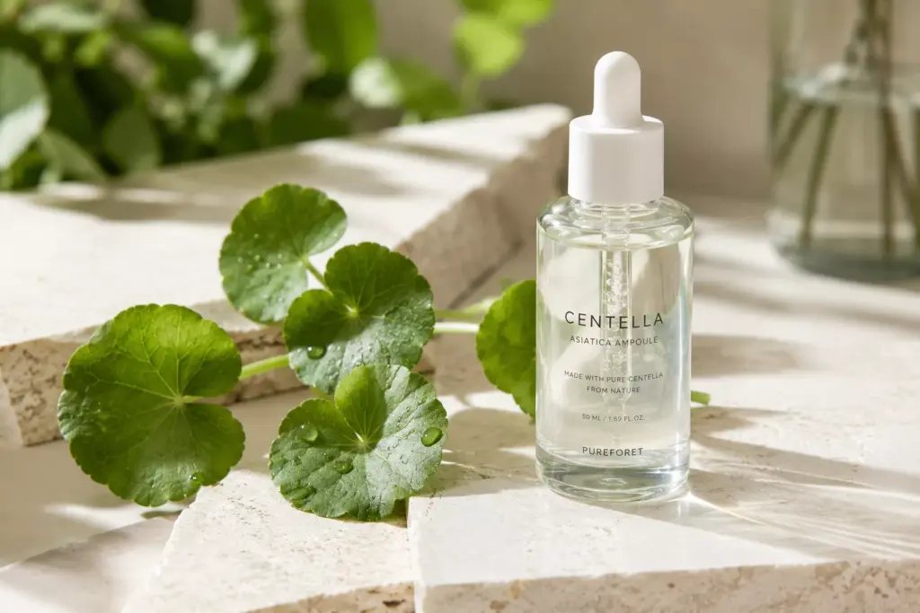 Centella vs Panthenol: Which Barrier Restorer Actually Heals Your Skin? 1 A minimalist flat lay of green Centella Asiatica leaves next to a glass skincare dropper bottle, comparing ingredients for Centella vs Panthenol efficacy.